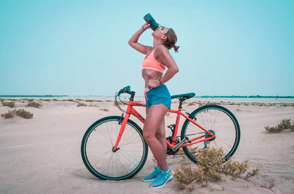 Mujer en bicicleta tomando agua